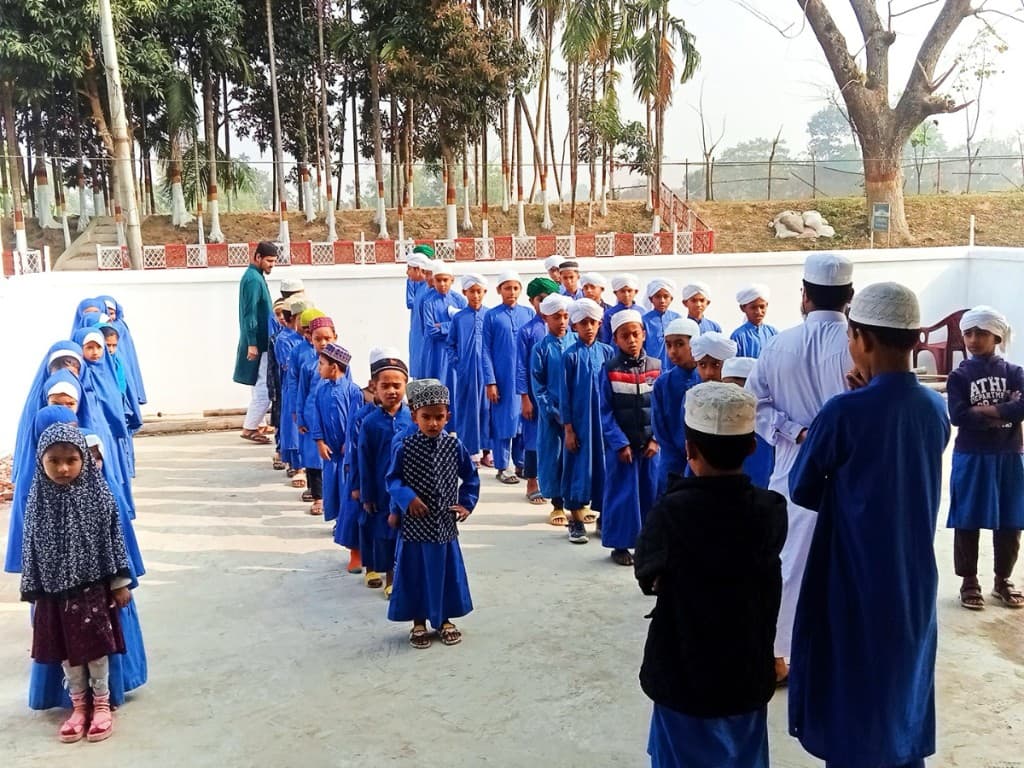 Madrasa students lined up in a courtyard in blue uniforms